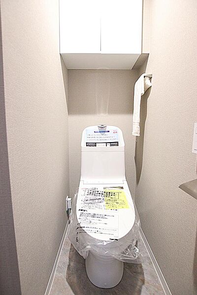清潔感のあふれるトイレ空間。トイレットペーパーなどを隠せる便利な上部吊戸棚付き