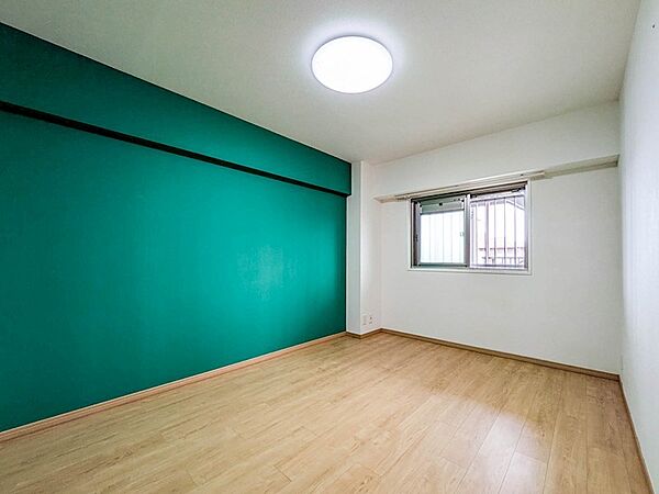 深緑のアクセントクロスがおしゃれな約6.5帖の洋室1。北側のお部屋ですがエアコン設置も可能です。