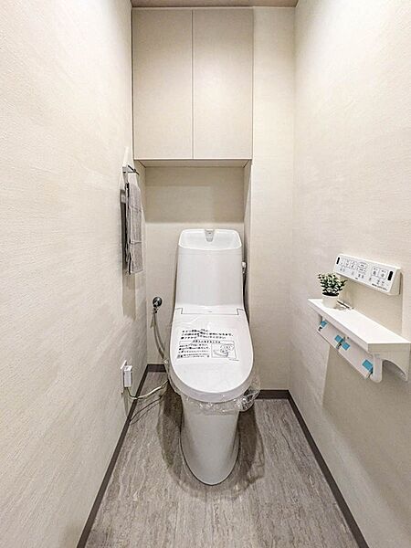 温水洗浄機能付きトイレに新規交換。上部に吊戸棚を備えており、ストック類をすっきり収納できます。