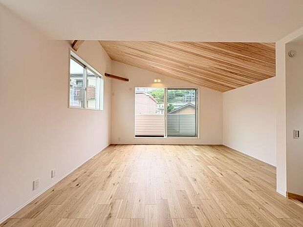 リビングは木目の天井が特徴的で温かみのある雰囲気です。大きな窓からは自然光がたっぷりと入り開放感があります。フローリングの質感もやさしくシンプルで使いやすい空間です。