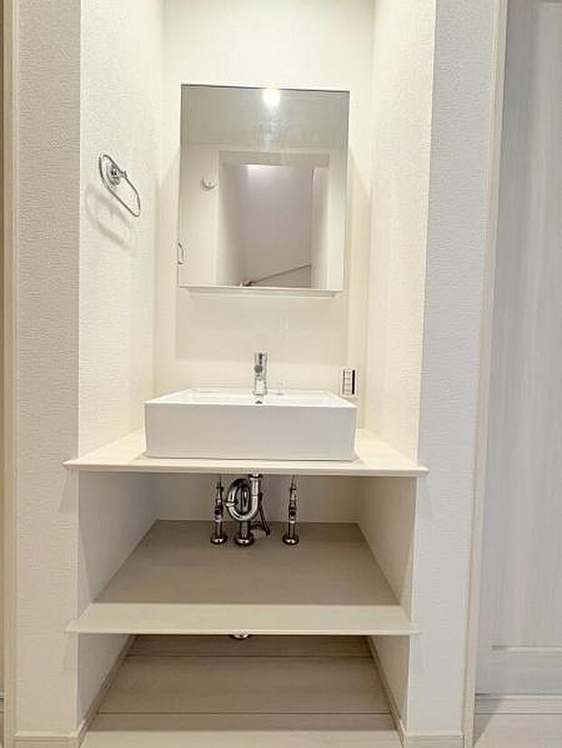 すっきりとしたデザインの洗面台が特徴的です。シンプルな空間に大きな鏡が配置され明るい雰囲気です。収納スペースも設けられており日常使いに便利です。