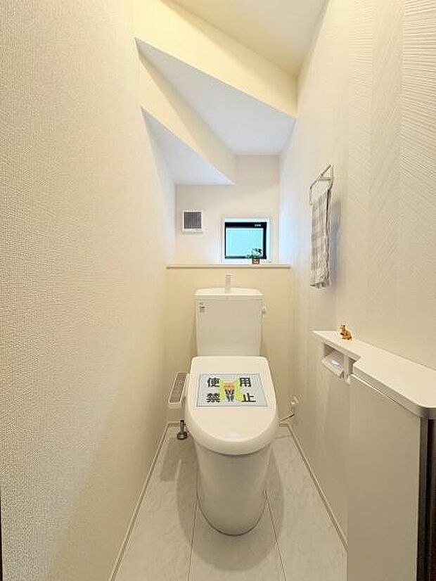 明るい光が差し込むトイレ空間です。壁面もすっきりとしており清潔感があります。窓付きで換気もしやすい設計です。コンパクトながら必要な設備がまとめられていて使いやすいです。収納スペースも備わっています。
