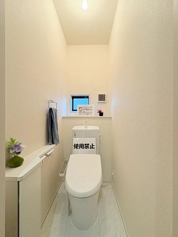 明るい照明と清潔感のある内装が特徴のトイレです。小窓が設置されており換気もしやすい設計です。コンパクトながらも収納スペースが確保されています。スタイリッシュな空間が広がります。