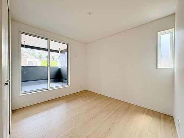 大きな窓から明るい光が差し込む寝室です。シンプルで広々とした空間が特徴的です。白を基調とした内装で清潔感があります。バルコニーへのアクセスが便利です。快適な環境を演出できる一部屋です。