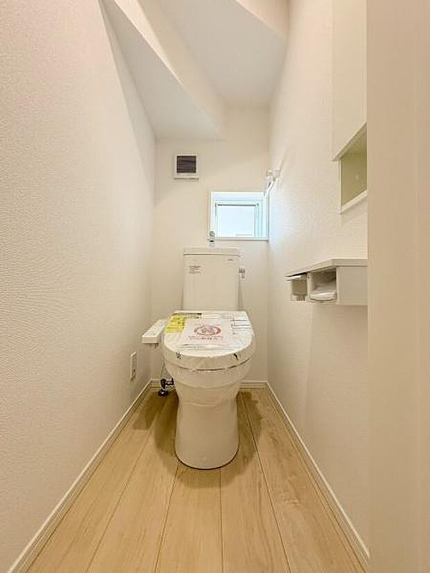 明るくシンプルな内装で清潔感のあるトイレ空間です。小窓が備わり自然光が差し込む設計です。壁面の収納スペースやペーパーホルダーも配置され使い勝手を意識したつくりです。