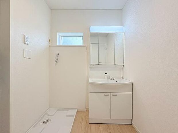 明るくシンプルなデザインが特徴の洗面台・洗面所です。使いやすい三面鏡と収納スペースが備わっています。室内は清潔感を感じられる白を基調とした内装です。床の木目調がアクセントになっています。