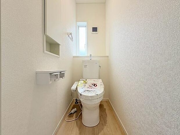 清潔感のある白を基調としたトイレ空間です。窓からの採光があるため明るく開放的な印象となっています。床にはナチュラルカラーのフローリングが使用されています。