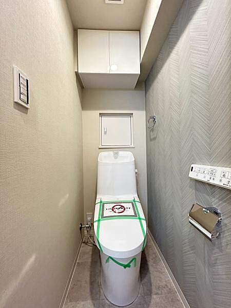 一部にアクセントクロスが採用されており、単調になりがちなトイレをモダンでおしゃれな空間に仕上げています。トイレットペーパーのストックや掃除用具などを収納できる吊戸棚付です。