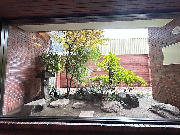 赤茶色の重厚感あるレンガ壁に囲まれた空間に、豊かな植栽や庭石、趣のある灯籠が配された風情ある中庭スペース。日常のなかに和みのエッセンスを取り入れた、落ち着きのある共用デザインが魅力です。