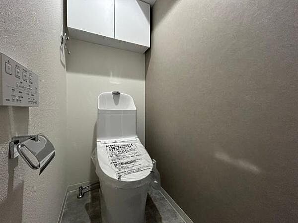壁の片面に落ち着いたグレージュ系のクロスが使われており、閉鎖的になりがちなトイレをモダンで落ち着く空間に仕上げています。