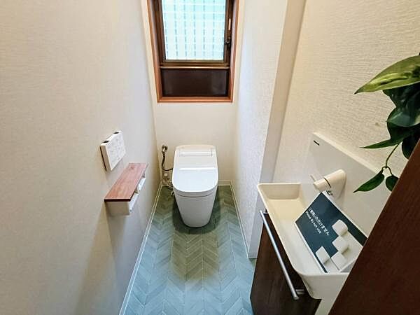 爽やかなグリーンのヘリンボーン柄床とスタイリッシュなタンクレストイレが調和した空間。独立型の手洗いカウンターも備えた、清潔感あふれる快適なトイレです。