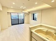 天井の一部を高くした「折り上げ天井」に沿って間接照明が仕込まれており、柔らかな光が空間を包み込んでいます。白を基調とした壁紙に、トレンドである明るいライトカラーのフローリングが組み合わされています。