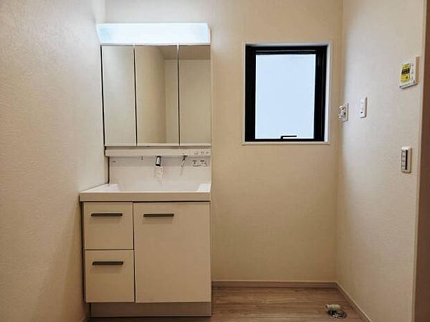 三面鏡収納タイプの洗面化粧台を標準装備した明るい洗面脱衣室。顔全体をしっかり照らす明るい照明や、ミラー裏の豊富な収納スペースなど、身支度をスムーズにする機能が充実しています。