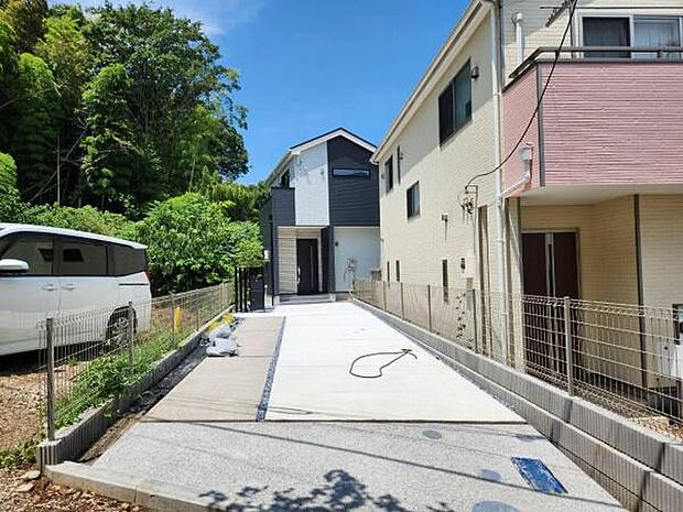 道路から奥まった静かな配置により、プライバシーと落ち着きある住環境を実現した住まい。ゆとりあるアプローチ兼カースペースの先には、豊かな緑を背に佇むスタイリッシュなモダン邸宅が広がります。