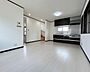 リビング/ダイニング：白を基調とした明るい内装に、ダークカラーの建具とシステムキッチンが引き締まる、洗練されたモダンスタイルのLDKです。フロアやクロスの清潔感とシックなアクセントが調和し、上質な空間を演出します。