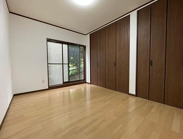 温かみのある明るい木目の床と、落ち着きのある上品なダークブラウンのクローゼット扉が、シックで洗練された寝室空間を演出します。
