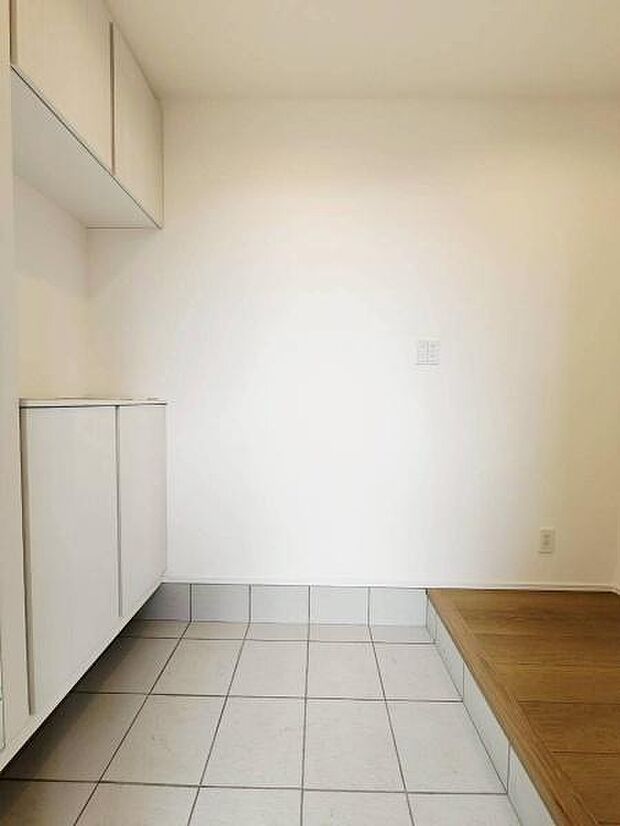 白を基調としたシンプルで洗練されたデザインの玄関です。明るい壁紙と清潔感のある床タイルが、訪れる人を爽やかに迎えます。