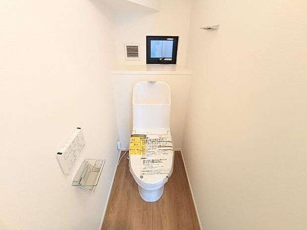 白で統一された壁面と温かみのある木目調フロアが調和する、心地よいトイレ空間。奥には小窓が配置されており、自然光を取り入れながらいつでもしっかりと換気が行えます。