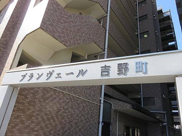 「プランヴェール吉野町」の文字が印象的なスタイリッシュな館銘板が、住まいの顔として上質な存在感を放ちます。落ち着いたアースカラーのタイル外壁と組み合わさり、品格を感じさせるアプローチデザインです。