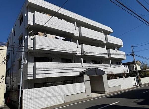青空に映える白タイルの重厚感ある低層レジデンス。すっきりと整えられたアプローチやエントランス周りは管理体制の良さを物語り、日々心地よくご帰宅いただけます。