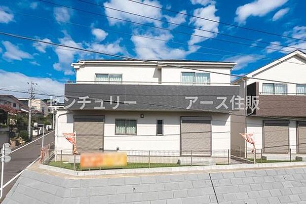 青空が映える、ツートンカラーのモダンな外観。広い駐車スペースと温かみのある玄関が迎える、新しい暮らしの舞台。