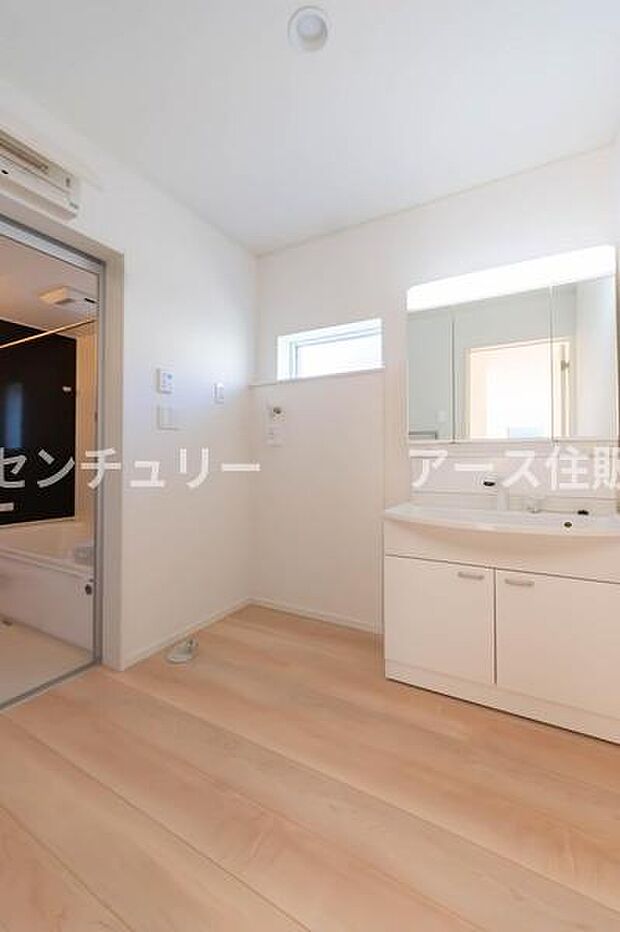 白を基調とした清潔感あふれる洗面室。浴室のモダンなアクセントウォールが、日々の疲れを癒やす上質な空間を演出します。