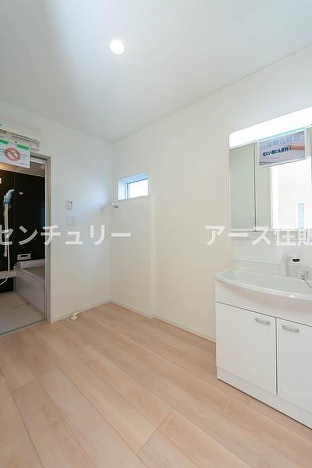 白を基調とした清潔感あふれる洗面室。浴室のモダンなアクセントウォールが、日々の疲れを癒やす上質な空間を演出します。