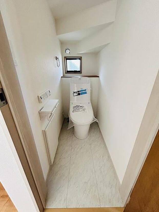コンパクトな空間ながらも窓付きで採光が期待できるトイレです。手洗いスペースや収納も完備しており使い勝手に配慮されています。清潔感のある内装が印象的です。落ち着いた雰囲気の空間となっています。