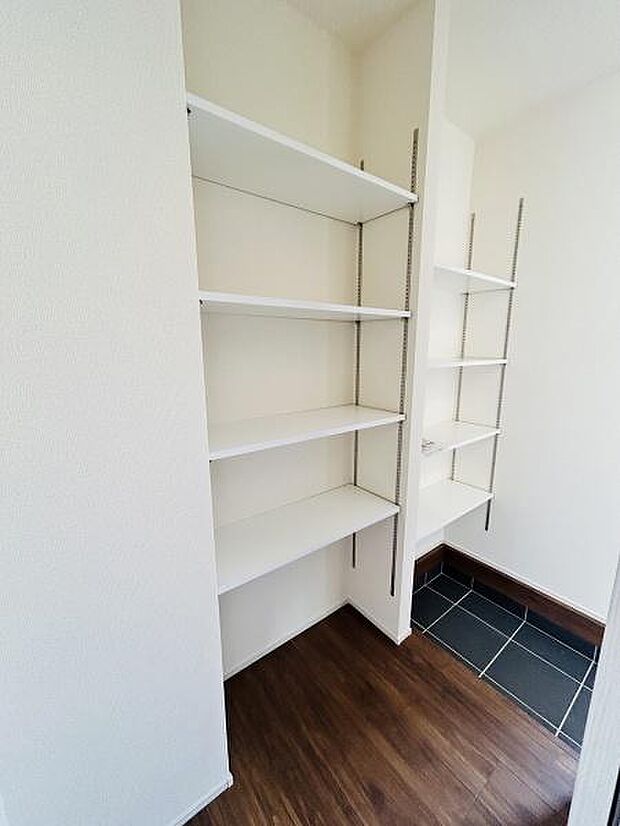 玄関には便利な可動式棚が備え付けられており使い方に合わせて高さ調整が可能です。白を基調とした内装で清潔感があります。床材とタイル部分のコントラストが空間にメリハリを与えています。