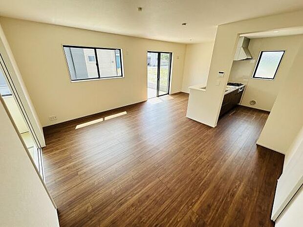 大きな窓から光が差し込むリビングです。フローリングが広がる開放的な空間となっています。隣接するキッチンへの動線もスムーズです。レイアウトの自由度が高い設計です。