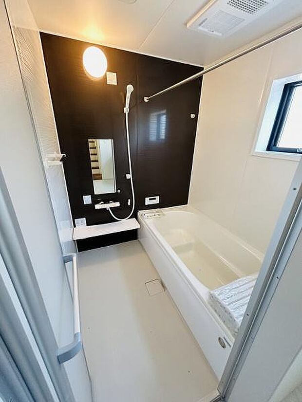 白を基調とした清潔感のあるバス空間です。壁のアクセントカラーがシンプルな雰囲気を引き立てています。窓があり換気しやすい仕様となっています。照明付きで明るさもしっかり確保されています。