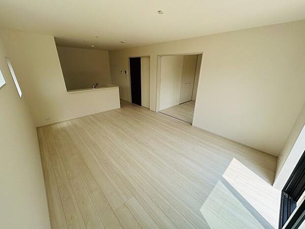 リビングはシンプルな内装と明るい色合いのフローリングが特徴です。大きな窓から光が差し込み開放感があります。隣接するスペースとつながっているため空間が広く感じられます。