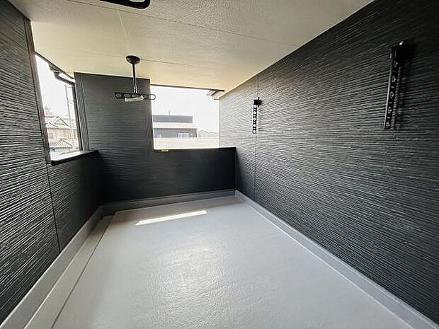 シックな色合いの壁が印象的なバルコニーです。ゆったりとした奥行きがあり開放感も感じられます。壁付けの物干し金具が便利に設置されています。天井照明付きで使い勝手も良好です。