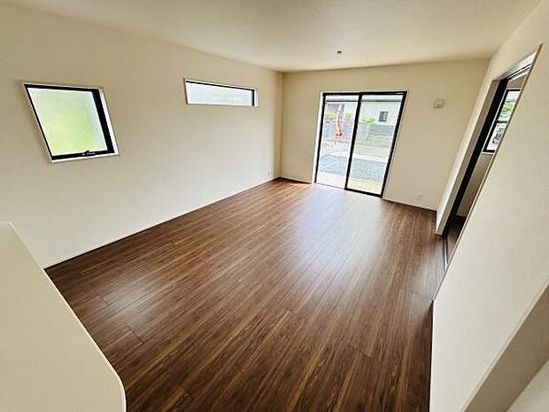 リビングは大きな窓から自然光がたっぷりと差し込み明るい空間が広がっています。床には落ち着いた色合いのフローリングを採用し壁と調和したシンプルなデザインです。