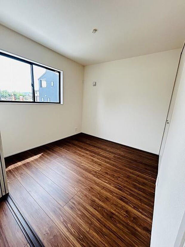 明るい光が差し込む洋室です。木目調フローリングが落ち着いた雰囲気を演出します。壁や天井が白く空間が広く感じられます。シンプルな形状でレイアウトもしやすいです。換気にも便利な大きな窓が特徴的です。