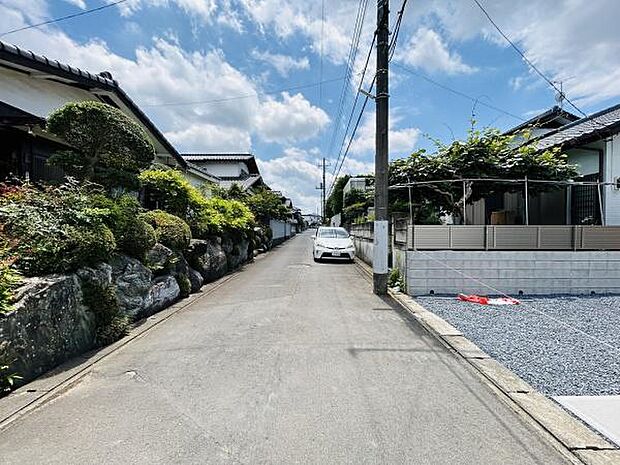 通り沿いに整った庭が並び落ち着いた雰囲気が広がります。車の通行も安心できる道幅があります。電柱や配線が整然としており住環境の印象も良好です。舗装された道路が続き移動にも便利です。