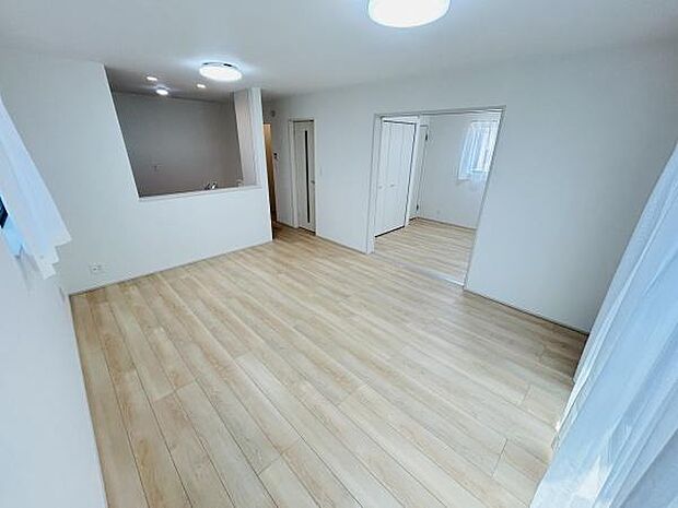 明るい床材が使用されており開放感のある室内です。ホワイトを基調とした内装が印象的です。広々とした空間が確保されていて使い勝手が良さそうです。リビングと他の部屋がゆるやかにつながっています。