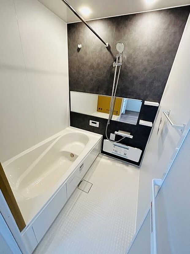 シンプルで落ち着いた色合いのバスルームです。大きな鏡が空間に広がりを感じさせます。清掃しやすい床材も魅力的です。換気扇と明るい照明が機能的な印象を与えます。高いデザイン性を感じるバスルームです。