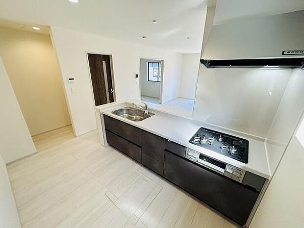 シンプルな内装とダークブラウンのキッチンが印象的です。開放感のある空間で動線もスムーズに確保されています。窓からの光が入りやすく室内が明るく感じられます。
