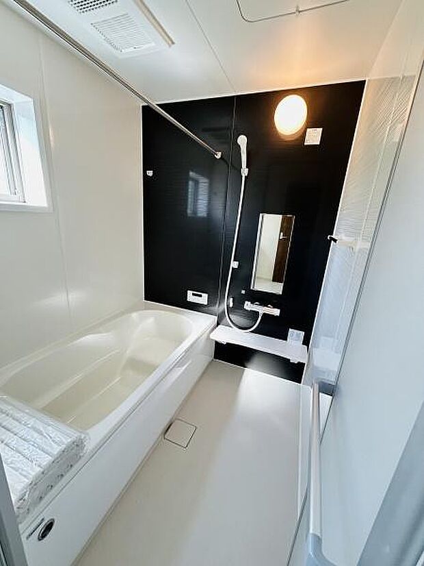 浴槽と洗い場が広々としたバス空間です。モノトーン調のデザインが洗練された印象を与えます。換気用の小窓があり湿気対策も考えられています。照明が明るく浴室内がすっきり見えます。