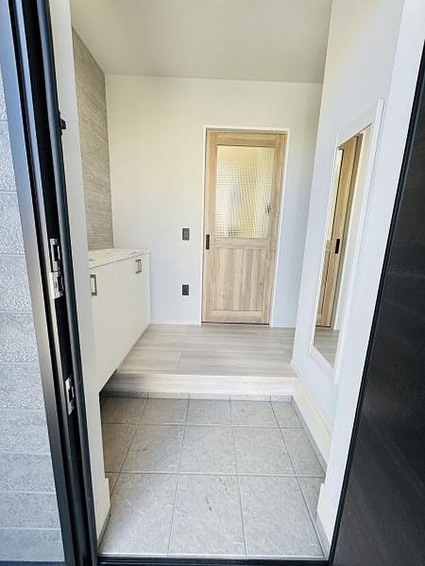 明るい玄関スペースが広がりシンプルで清潔感のあるデザインです。収納スペースも充実しており日々の出入りが快適に行えます。大きな鏡が印象的で身だしなみのチェックにも便利です。