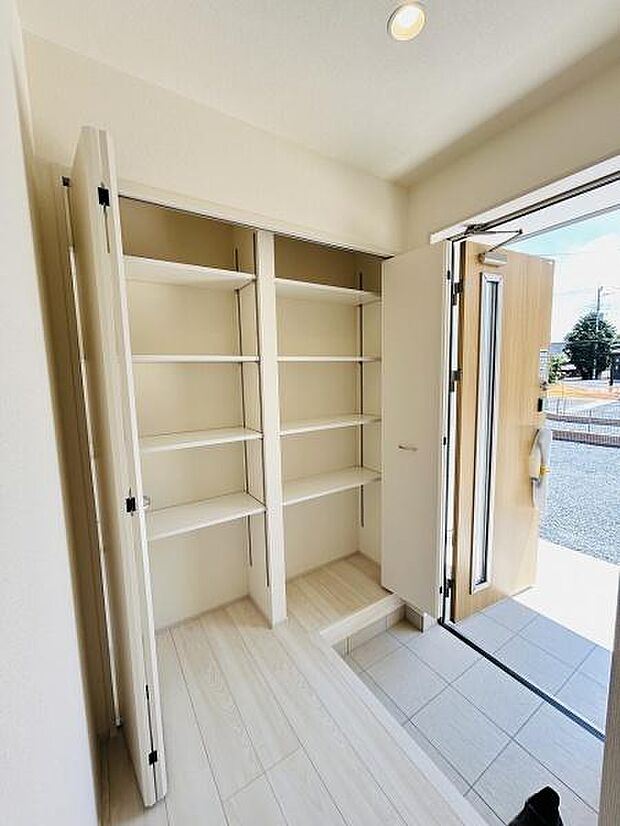 明るい玄関に便利な収納棚が設置されています。オープンな空間で荷物の出し入れもしやすいです。洗練された色合いが空間を広く見せています。玄関ドアも採光性に優れ爽やかな印象です。