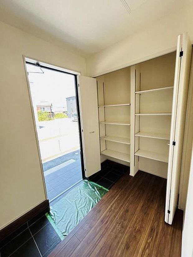 玄関には使いやすい収納スペースが備え付けられておりすっきりとした印象です。大きな扉からは自然光が差し込み明るい空間となっています。床は異なる素材で区切られていてメリハリのあるデザインが特徴です。