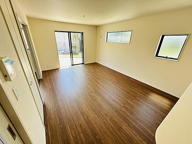 リビングには大きな窓が配置されており開放感のある空間が広がっています。木目調の床材が落ち着いた雰囲気を演出しています。壁や天井も明るい色合いで部屋全体が明るく感じられます。