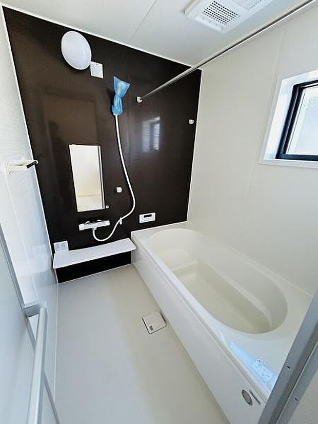 シンプルで清潔感のあるバスルームです。壁面のアクセントカラーが落ち着いた印象を与えています。小窓が設けられているため明るさと換気が確保されています。浴槽と洗い場がゆったりとした配置になっています。