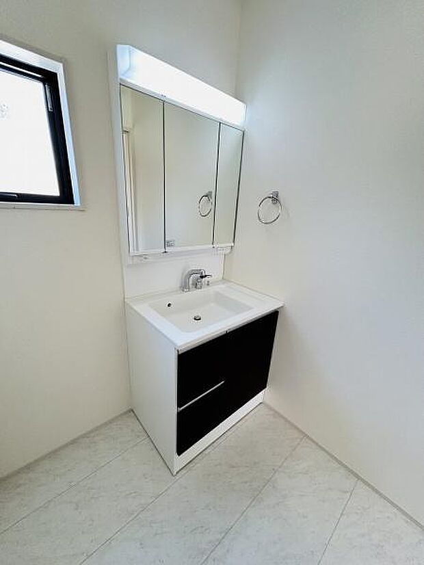 シンプルなデザインの洗面台が空間をすっきりと見せます。ミラーキャビネット付きで収納にも便利です。明るい印象の床や壁で清潔感があります。小窓から自然光が入り日中も明るく使いやすいです。