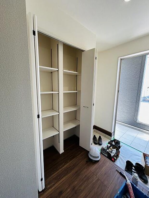 玄関には使い勝手の良い収納スペースが備えられています。棚が複数あり整理整頓しやすい設計です。明るい採光が入る空間で室内もすっきりとした印象です。玄関周りが広く感じられるレイアウトです。