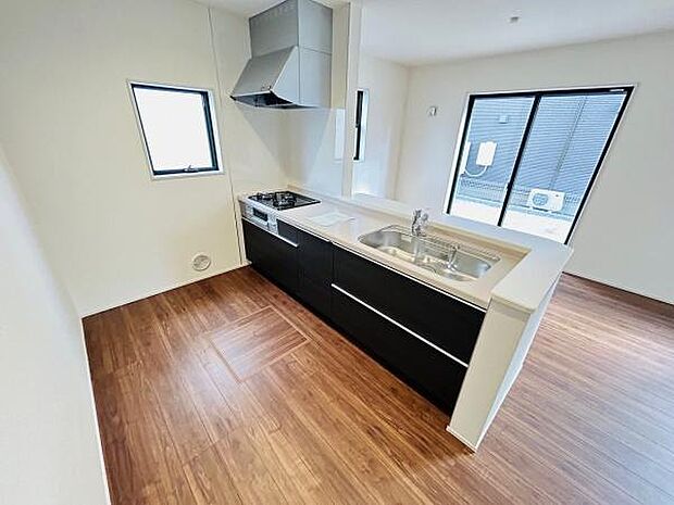 キッチンは窓が二面にあり明るい空間を演出しています。シンプルなデザインのシステムキッチンでお手入れもしやすいです。広々とした作業スペースが魅力です。床材のカラーが落ち着いた印象を与えます。