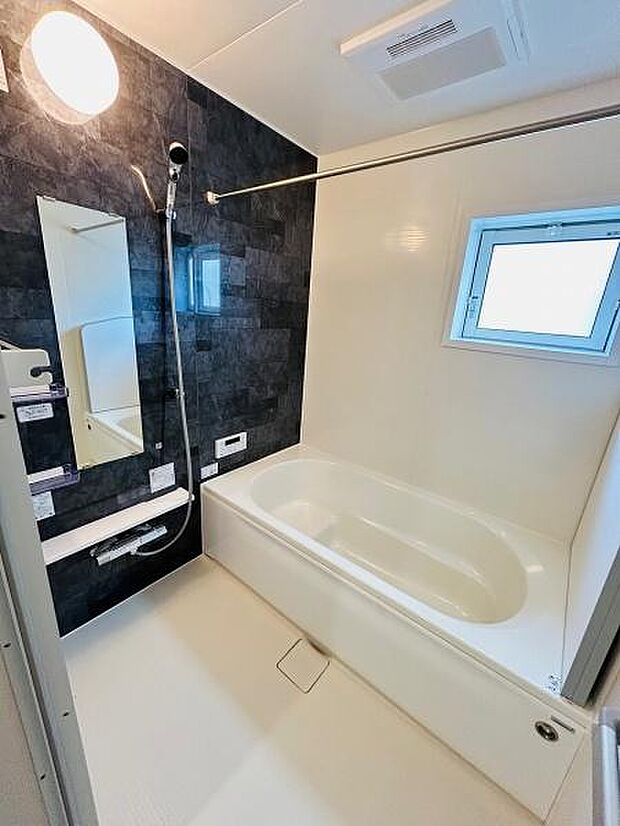 浴槽とシャワースペースがすっきりとしたレイアウトです。大きな窓があり換気や明るさを確保しやすい設計です。壁面のアクセントカラーが目を引くバスルームです。鏡や棚も使いやすい高さで設置されています。