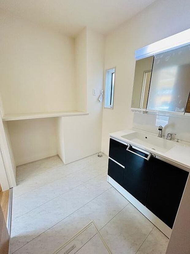 明るい色合いの床と壁が特徴のバスルームです。洗面台は広々としたカウンターが備わっています。収納スペースも充実しており使い勝手の良さを感じられます。窓があるため換気がしやすい設計です。